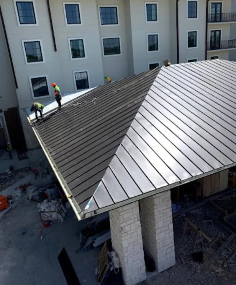 Crew installing standing seam metal roof panels on a commercial project in Bardmoor